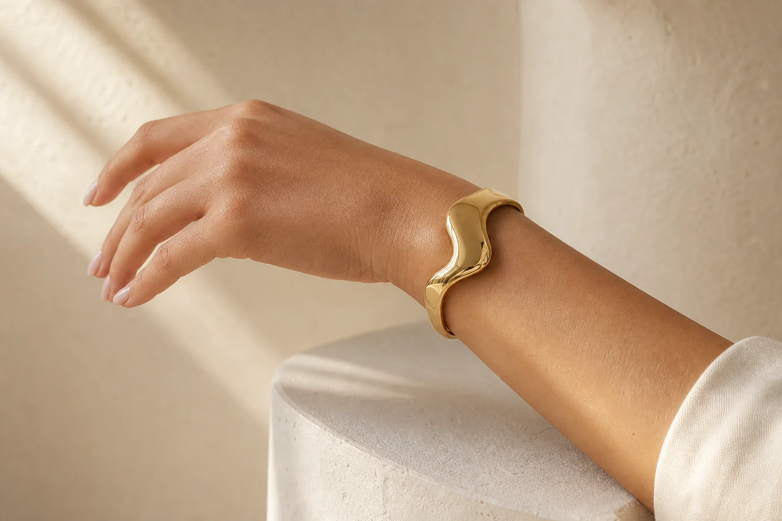 Sculptural gold cuff bracelet shown in a polished lifestyle campaign image