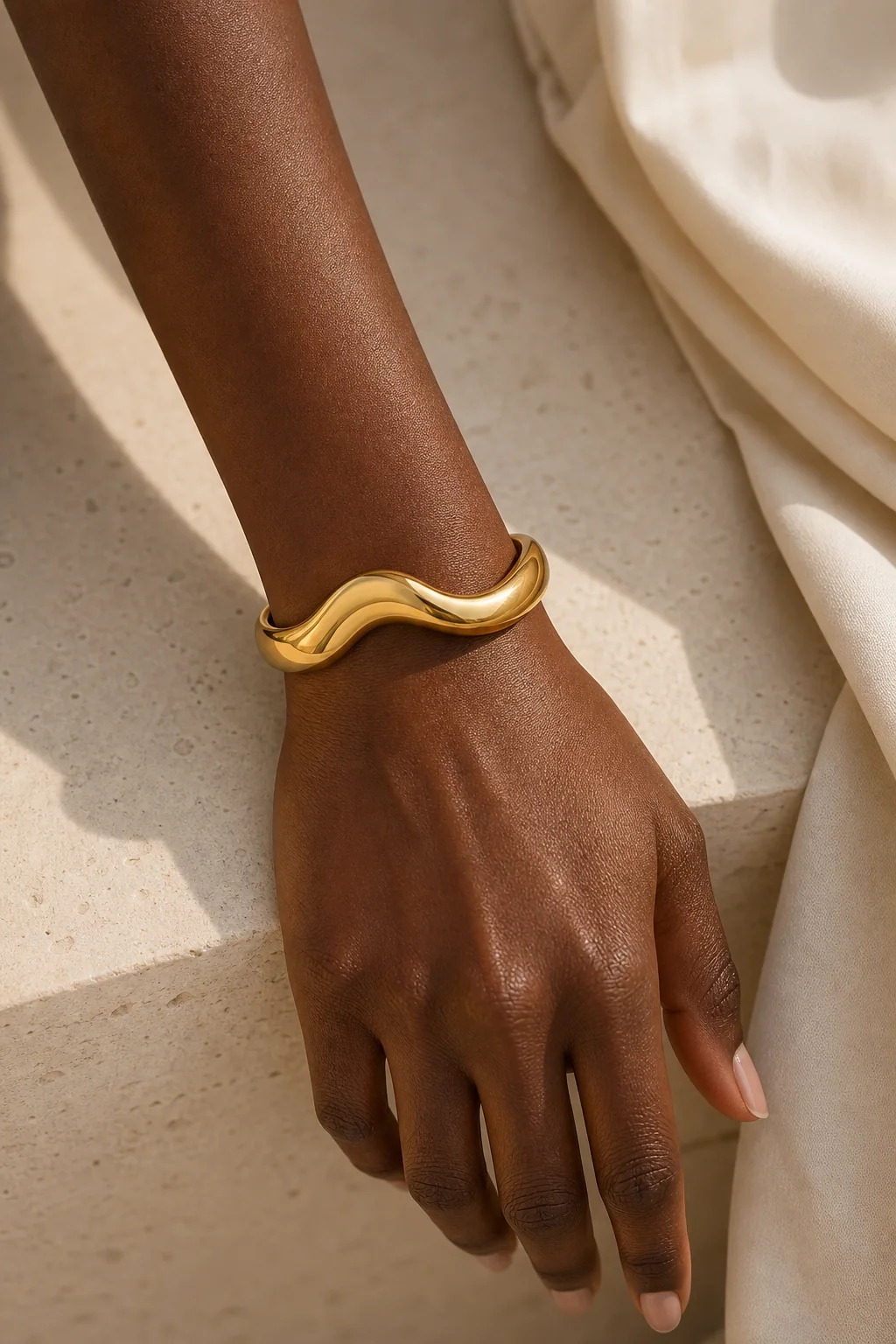 Gold wave cuff bracelet placed on a model's wrist
